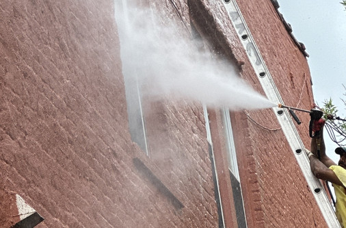 Professional power washing service cleaning exterior walls of a commercial building