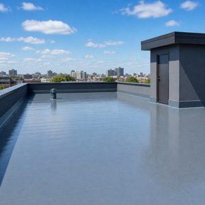 worker performing flat roof waterproofing using coating system on concrete roof surface
