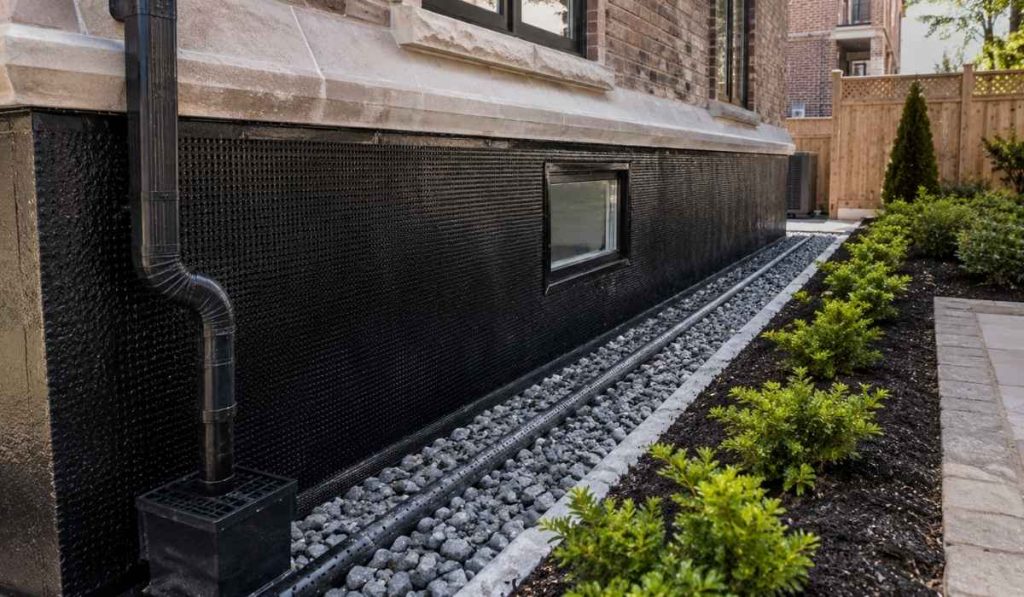 Exterior basement waterproofing system with waterproof membrane and drainage installation around NYC home foundation