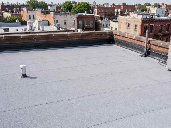Professional roof repair in progress on a flat residential rooftop, showing a contractor repairing damaged roofing membrane to prevent leaks and water damage. Expert roof repair services available throughout Brooklyn, Queens, Manhattan, Bronx, and Staten Island.
