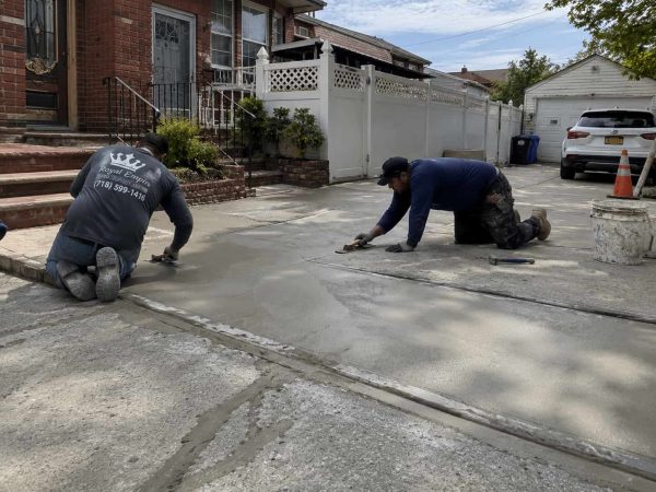 Professional driveway repair service in NYC with contractors restoring a damaged concrete driveway using quality repair techniques and materials.